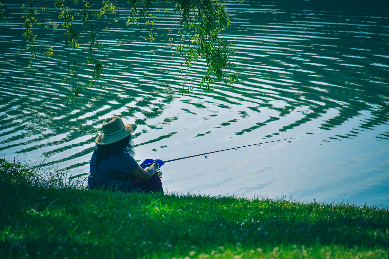 woman sitting in grass fishing in the early morning