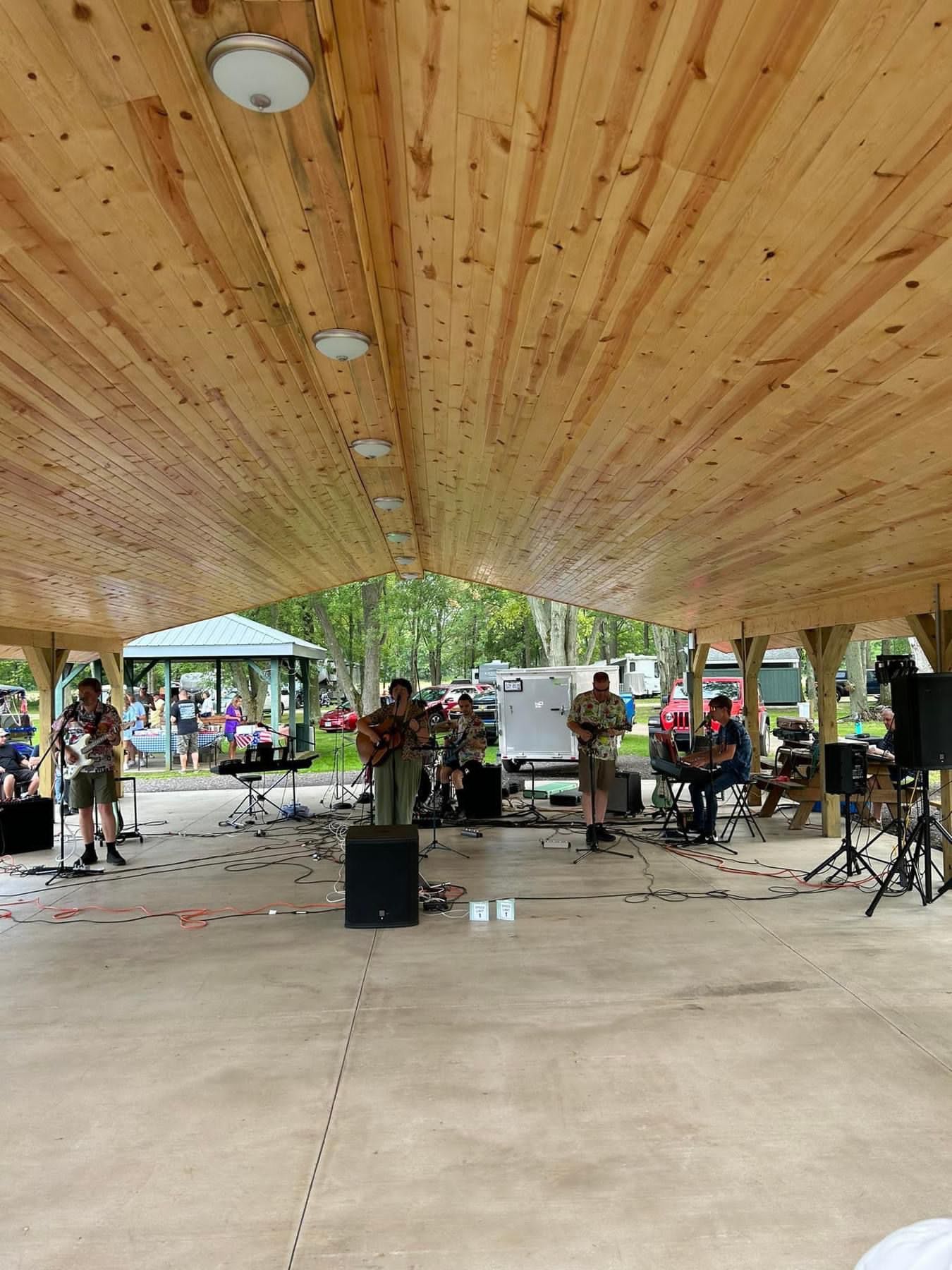 the speed limit band playing under a pavilion at a potluck